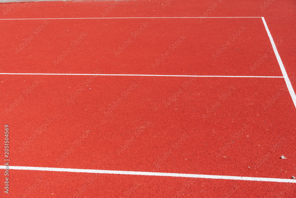 Fototapeta premium Bright Red Tennis Court Surface Inviting Players for a Lively Match Under the Clear Blue Sky in the Afternoon Sun