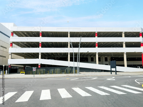 Modern multi level parking garage structure with empty road and crosswalk outdoors