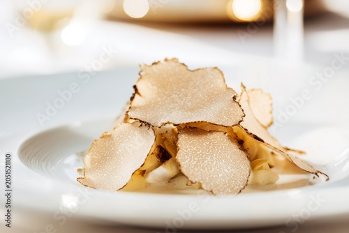 truffle luxury cuisine concept. Gourmet dish featuring thinly sliced truffles atop creamy base with garnishes, elegantly presented on white plate