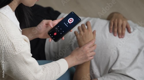 Woman calling emergency service to aid unconscious man lying on the floor