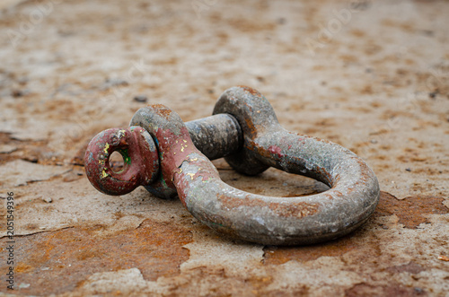 Close-up view of a bow shackle lying on a steel work surface at an offshore repair yard. The image shows a commonly used lifting and rigging component employed for connecting slings, chains