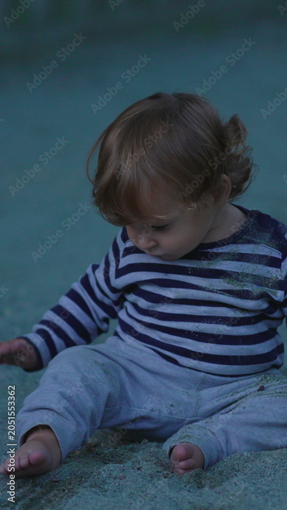Naklejka premium Child quietly playing with sand inside playground sandbox during peaceful outdoor afternoon capturing tactile learning, concentration
