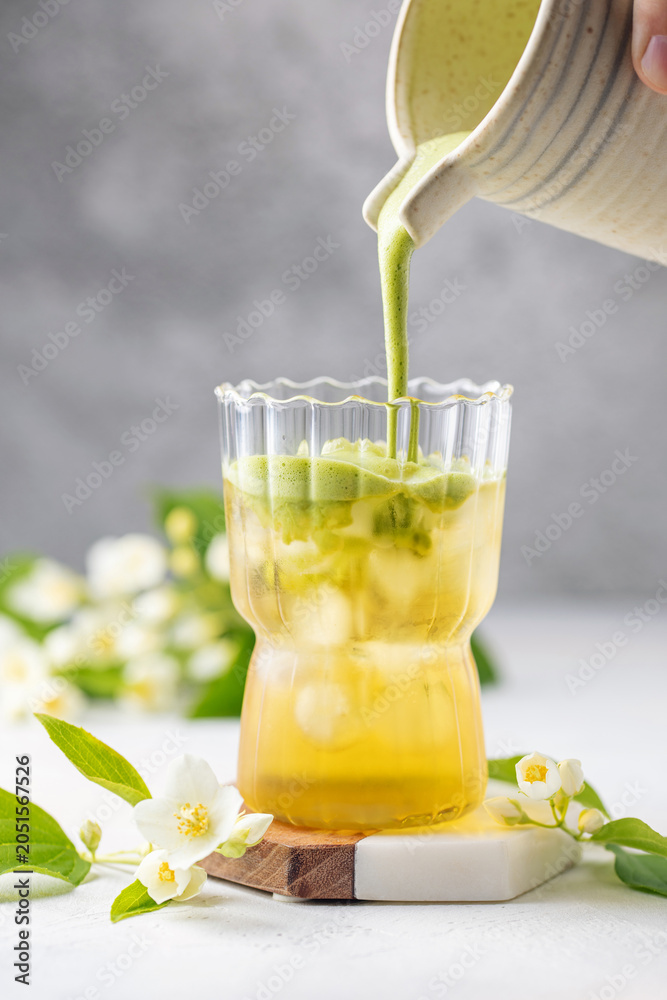 Fototapeta premium Green jasmine tea with macha latte in glass with jasmine flowers. Trendy drink