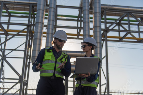 Industrial Engineers Inspecting Construction Site with Laptop, engineering teamwork, industrial inspection, project management and modern construction technology.