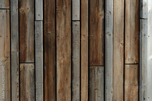 Detail of aged sports hall cladding featuring vertical timber planks in gray and brown