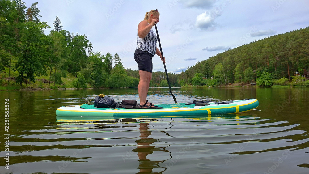 Naklejka premium Woman on a paddleboard enjoying summer vacation on a mountain lake.
