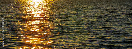 Tableau sur toile Golden sunlight reflecting on calm water surface during sunset, creating a shimm