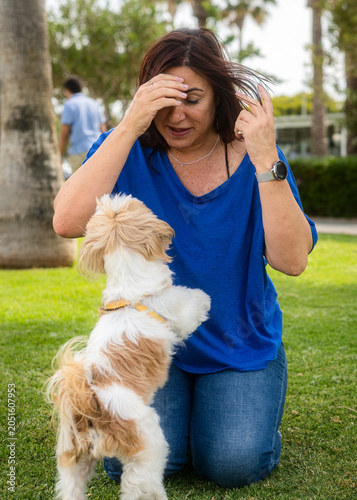 A young woman plays with her energetic Shih Tzu in a park. A cheerful lifestyle of a pet owner enjoying the outdoors.