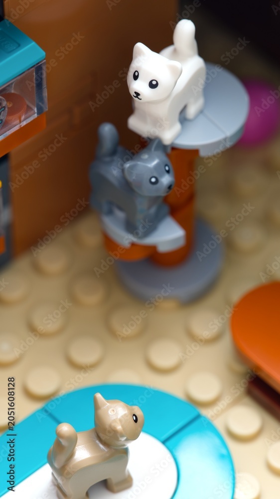 Obraz premium Tambov, Russian Federation - July 05, 2025 Three Lego cats in white, gray and tan colors play on a built scratching post and a colorful floor mat indoors.