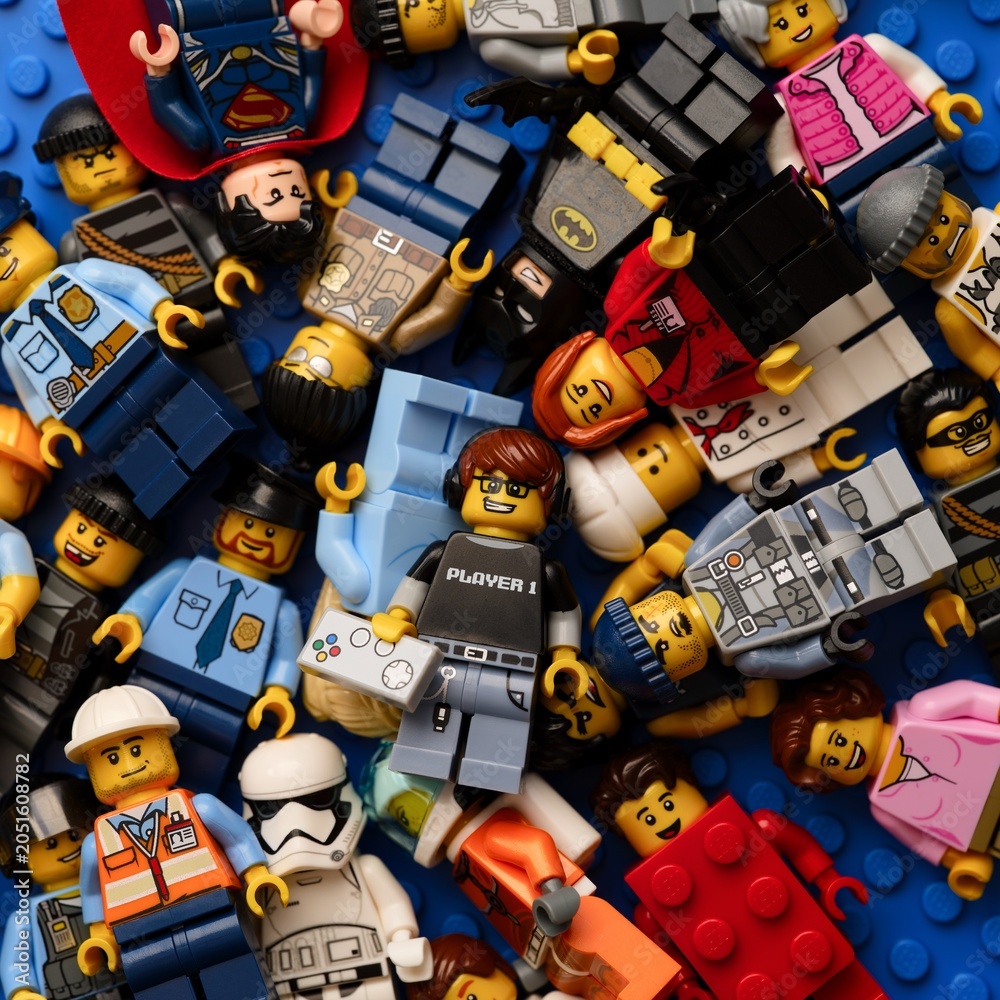 Obraz premium Tambov, Russian Federation - February 02, 2026 Heap of Lego minifigures on a blue baseplate background