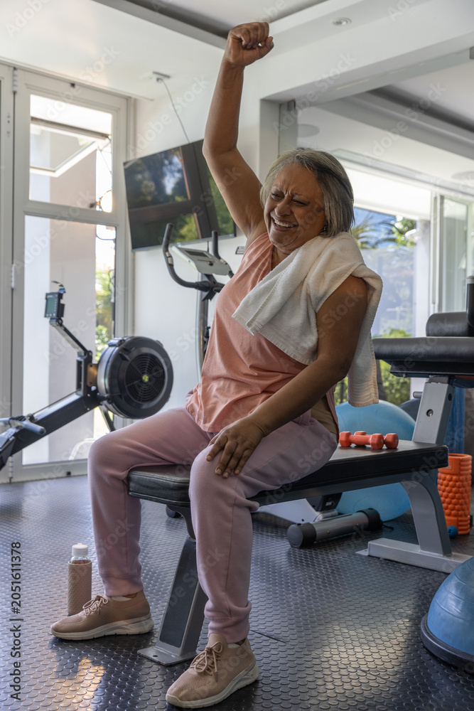 Naklejka premium Flat weight bench is holding towel and orange dumbbells in home gym near windows