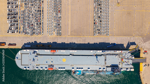 Bild auf Leinwand Large cargo ship moored at a dock, loading and unloading new automobiles while n
