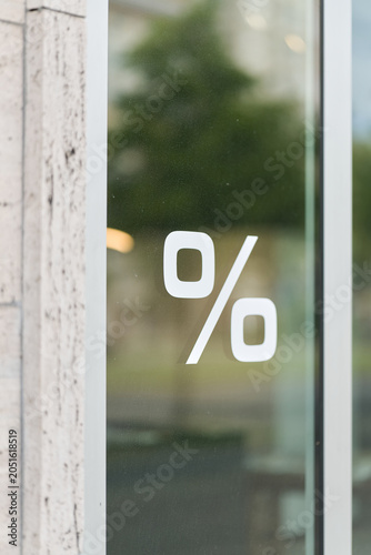 Prozentzeichen an der schmutzigen Schaufensterscheibe eines Geschäfts als Hinweis auf einen Sale