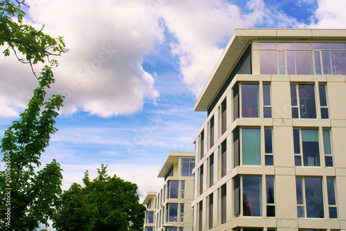 This is the bright facade of a big, modern office building on a cloudy spring day.