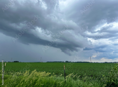 Dramatic storm clouds form over a rural farm field in summer 