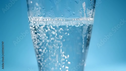 Sparkling Water Bubbles in Clear Glass on Blue Gradient Background