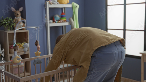 Foto Man bending over a wooden crib holding a baby and adjusting a blanket in a nursery inside a building; caregiving tenderness calm