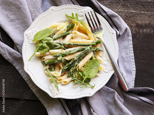 Penne pasta with asparagus and spinach on a white plate