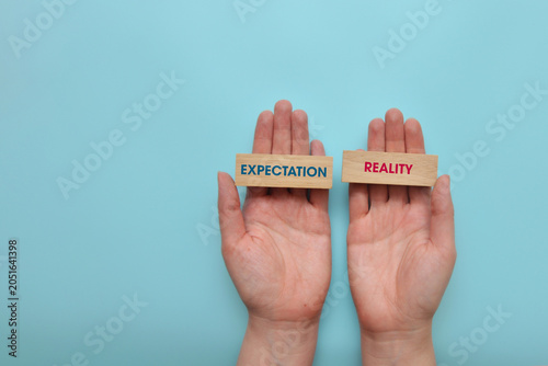 Tableau sur toile Expectation and reality labels held in hands on blue background