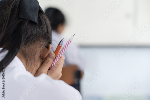 Stressed Student Holding Pens and Leaning Head on Hand During Exam
