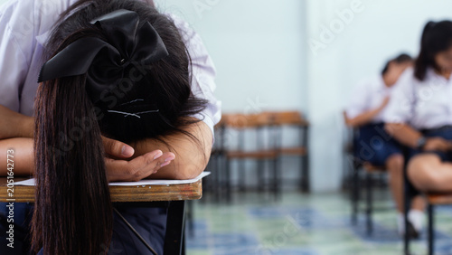 Exhausted Female Student Sleeping on Desk During Final Exam in Classroom