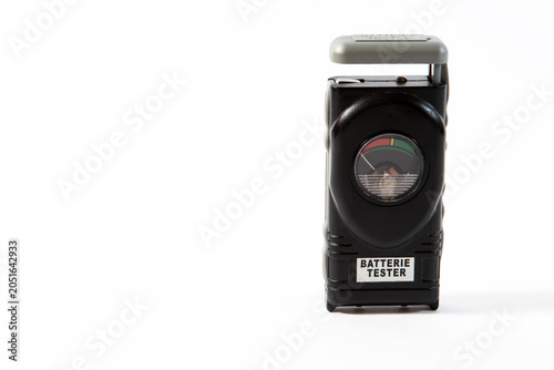 A vintage black portable analog battery tester with a german dial scale isolated on a clean white background