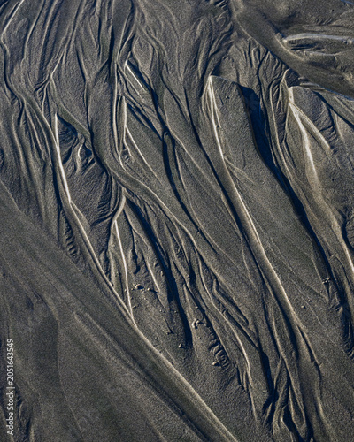 Natural pattern of water erosion in sand on beach creating flowing pattern