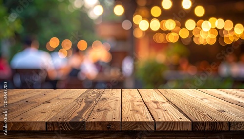 Close-up of a wooden tabletop against a blurred background with soft, warm bokeh lights and blurred figures