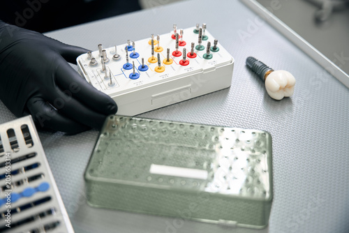 Foto Hands in black gloves holding dental implant tools kit indoors