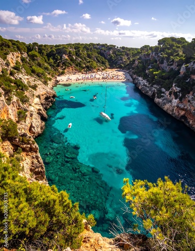 A serene turquoise bay nestled among lush greenery and rugged cliffs under a clear blue sky