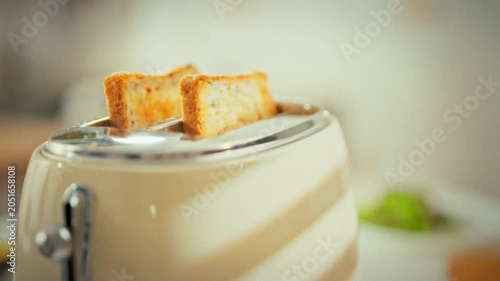 In a bright kitchen, a vintage toaster pops up golden toast, the sliced bread springing out as it finishes cooking. The warm aroma fills the room, highlighting simple, classic breakfast preparation