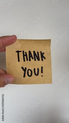 Hand holding kraft paper note with handwritten Thank You message on white background
