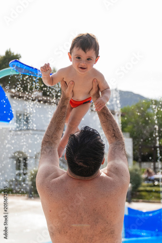 Father lifting son in pool for summer joy