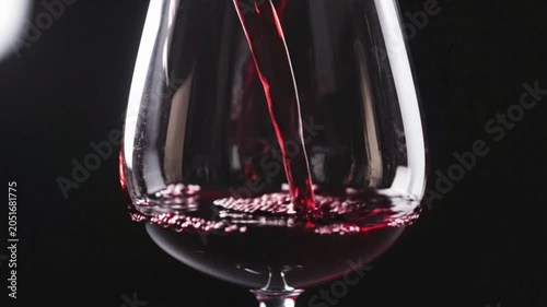 Red wine pouring into a glass over a dark background captures the rich color and flow of the wine