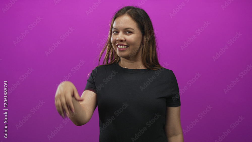 Obraz premium Woman waving hand in magenta studio while smiling and turning her head to the side; joyful confidence.