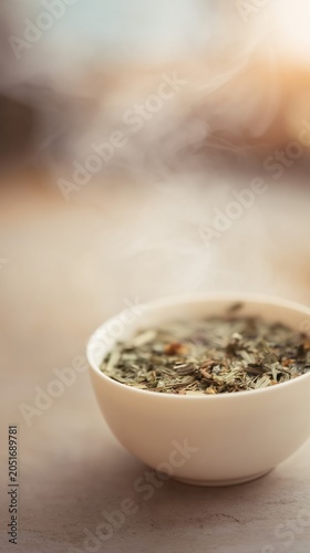 A ceramic bowl of warm herbal infusion emits gentle steam in soft earthy tones. This minimalist spa still life exudes calm, serenity, and tranquil wellness.