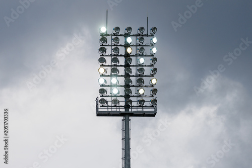 Photography Sport stadium light mast with glowing spotlights on a rainy day