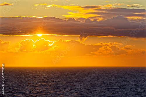 Obraz na plátně Golden sunset over calm ocean with low clouds