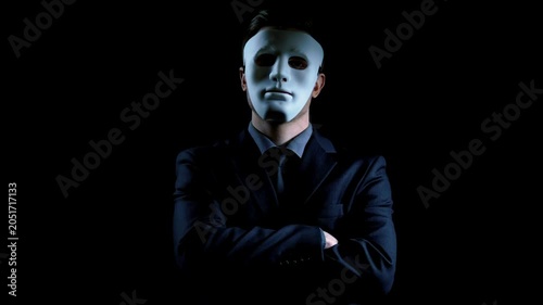 Cybercrime hacker Anonymous suit man in mask folding hands on black background illegal activity in 4K Ultra HD footage.
