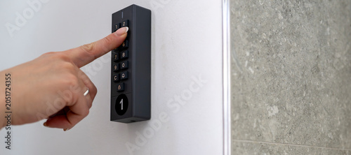 Woman using digital keypad lock for secure self check in at modern vacation apartment accommodation