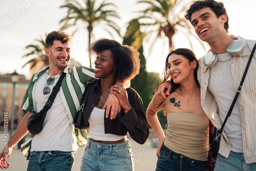 Diverse group of young adult friends walking together  embracing and laughing during a city vacation