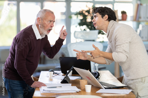Photos Men are standing on opposite sides of table and shouting at each other