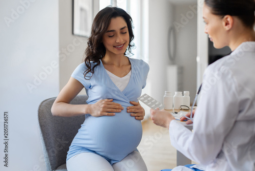 Obraz na płótnie Doctor discussing prenatal supplements with pregnant woman during maternity cons