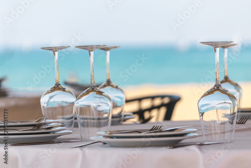 Konstfotografi Elegant seaside restaurant table setting with upside down wine glasses and ocean