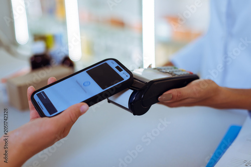 Foto Customer making contactless NFC payment using smartphone at pharmacy POS termina