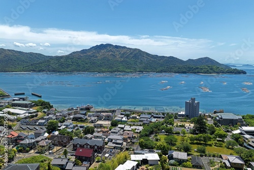 Aerial drone photo of coastal town and aquaculture rafts in Miyahama, Hiroshima, Japan