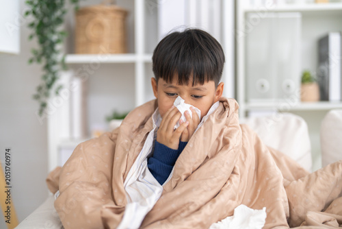 Bild auf Leinwand Young asian boy sneezing or blowing his nose and mouth with tissue, cold allergi