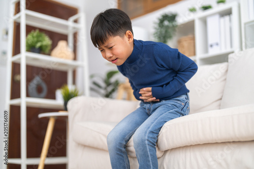 Foto Portrait of sick unhappy little child asian boy touching belly stomach with suff