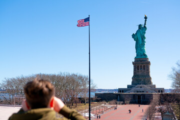 Tourist snaps a photo of  Statue of Liberty across the water