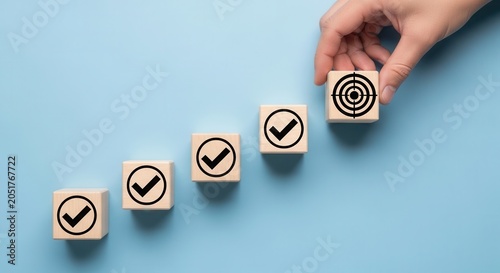 Hand placing target cube over checkmark blocks on blue background showing goal progression and success steps